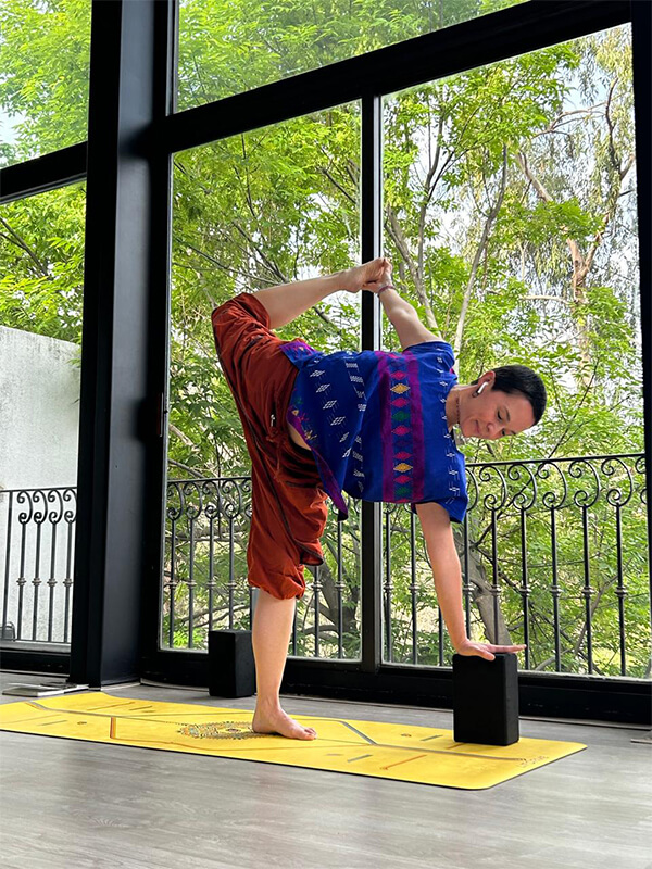 Instructor en guerrero tres con bloques de yoga en salón de Centro Kanda CDMX