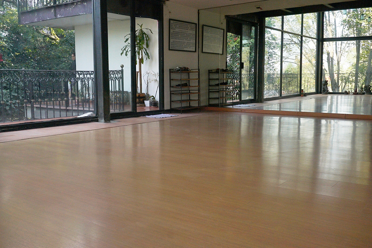 Salón de yoga vacío con piso de madera y espejo en Centro Kanda, Lomas de Bezares